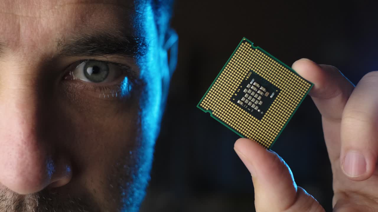 Male half face looking to CPU microchip processor on his hand, black background