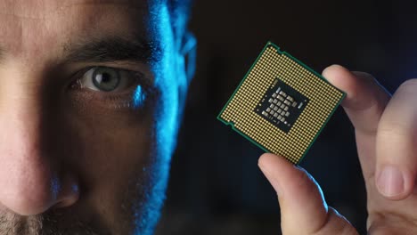 male half face looking to cpu microchip processor on his hand, black background