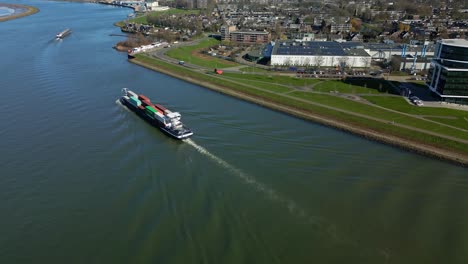 aerial view of container ship passing the suburbs of zwijndrecht through the canal in the netherlands