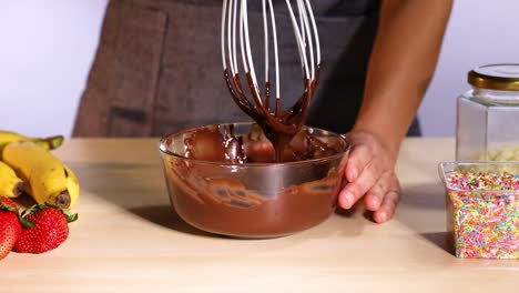 mixing chocolate with bananas and strawberries nearby