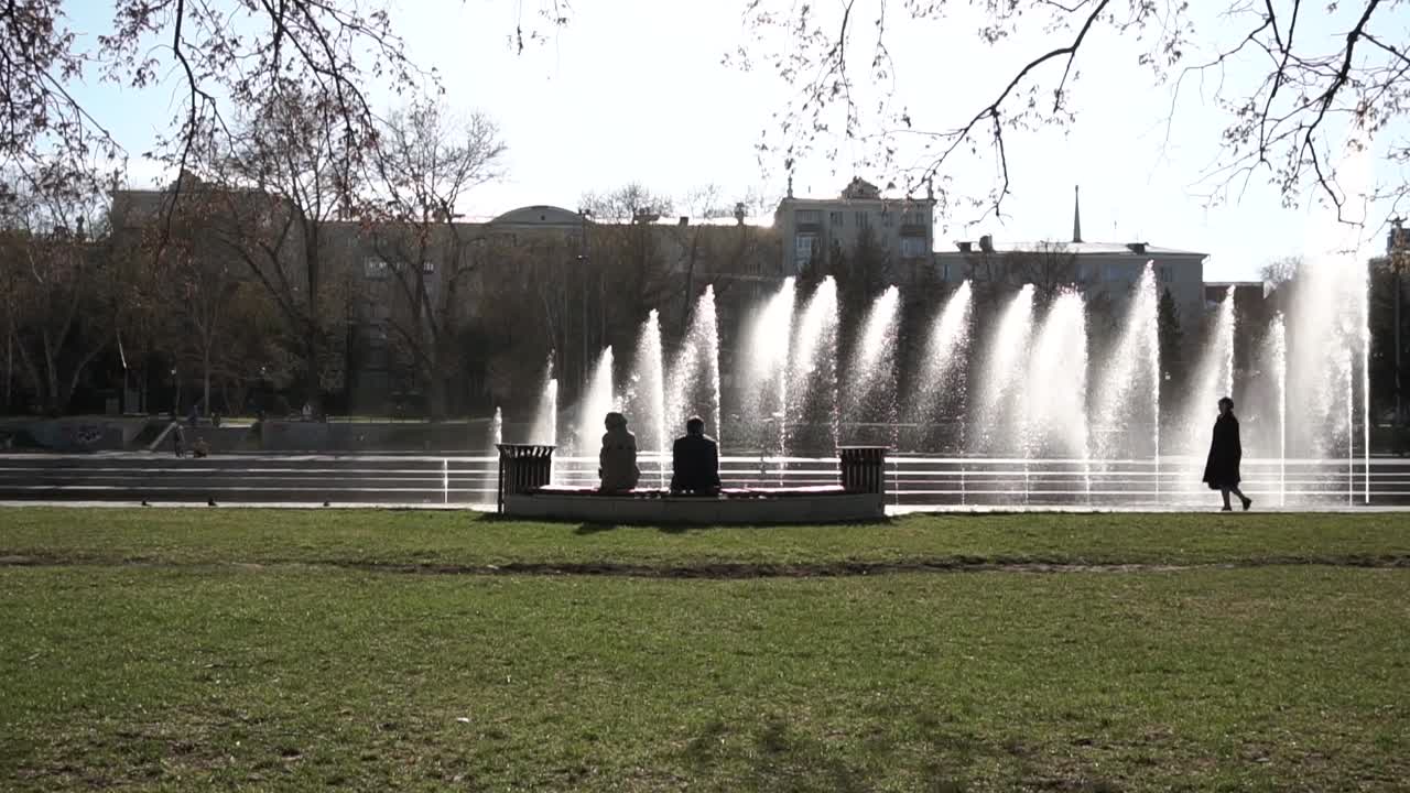 люди отдыхают у фонтана в парке