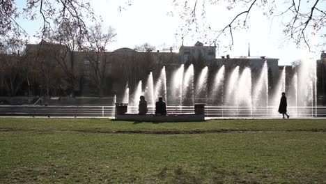 gente relajándose en una fuente del parque