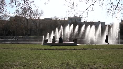 people relaxing at a park fountain