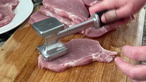 tenderizing pork cut with meat mallet tool - using meat pounder meat tenderizer to prepare slabs of pork and seasoning with salt for pork schnitzels recipe at home in kitchen slo-mo slow motion