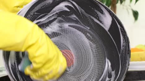 woman washing dirty frying pan in sink indoors closeup