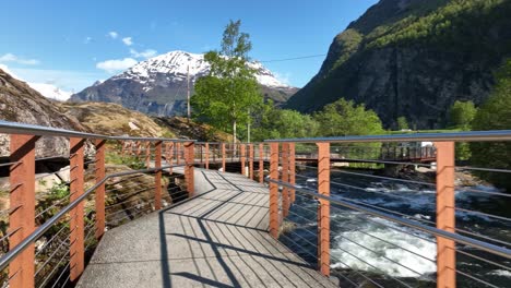 walking along walkway with railings beside geiranger river and norwegian fjord center in geiranger norway - tourist walking point of view