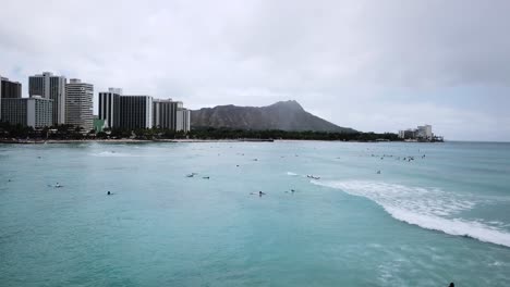 surfers surfing in waikiki beach for spring break in hawaii, aerial drone shot