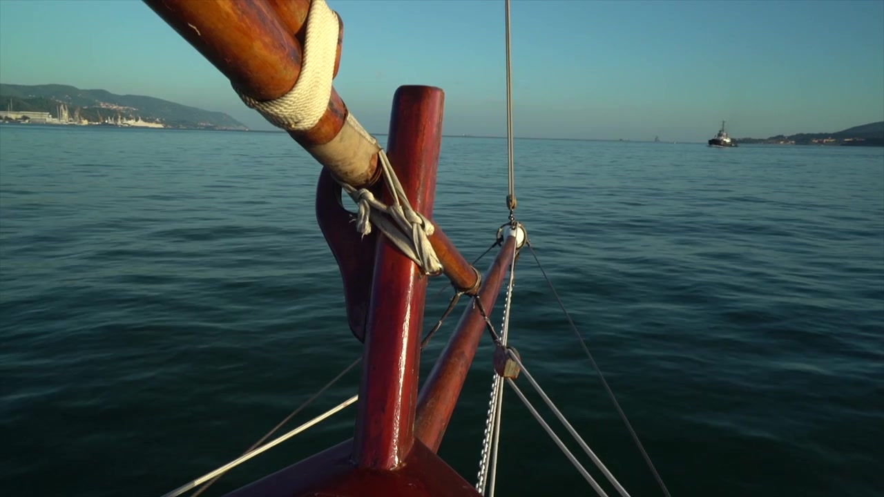 Punto di vista cinematografico dalla prua di una barca a vela in legno che naviga sul calmo mare blu. Splendido paesaggio costiero del Golfo dei Poeti in Liguria, Italia.