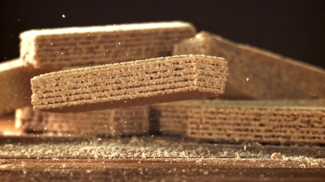 Biscotto wafer croccante che cade al rallentatore su superficie di legno