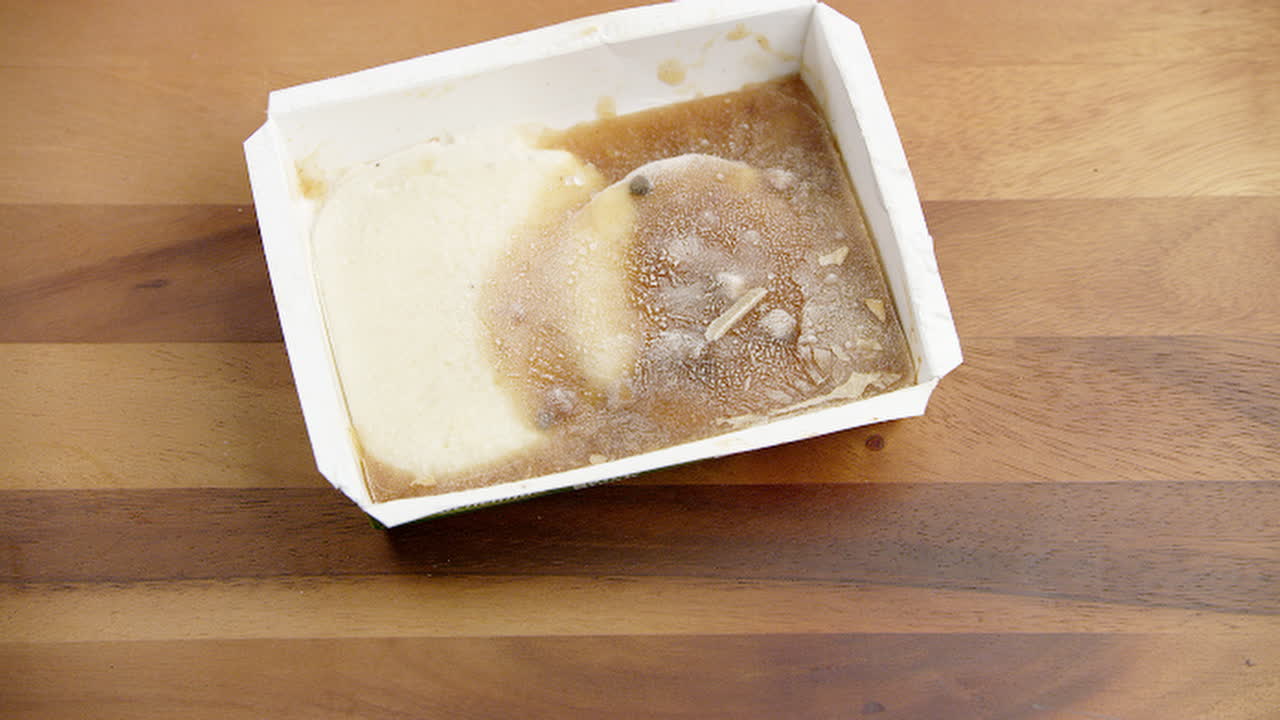 alimentos congelados poco saludables en un recipiente de comida de plástico, siendo recogidos para el almuerzo a toda prisa