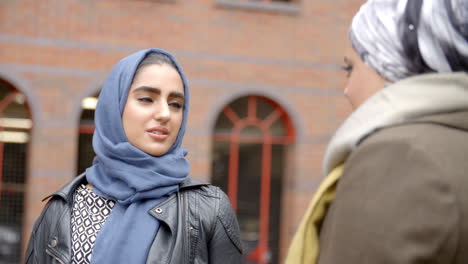 british muslim female friends meeting in urban environment