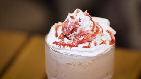 glass of strawberry milkshake with whipped cream and topping - macro close up, slider movement