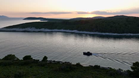 tranquil scene of a small boat gliding along a river between hills during sunset