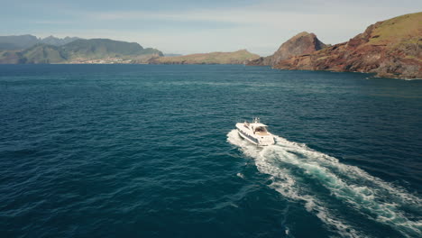 Aerial-of-boat-slowly-moving-through-blue-ocean-water-at-Madeira-island