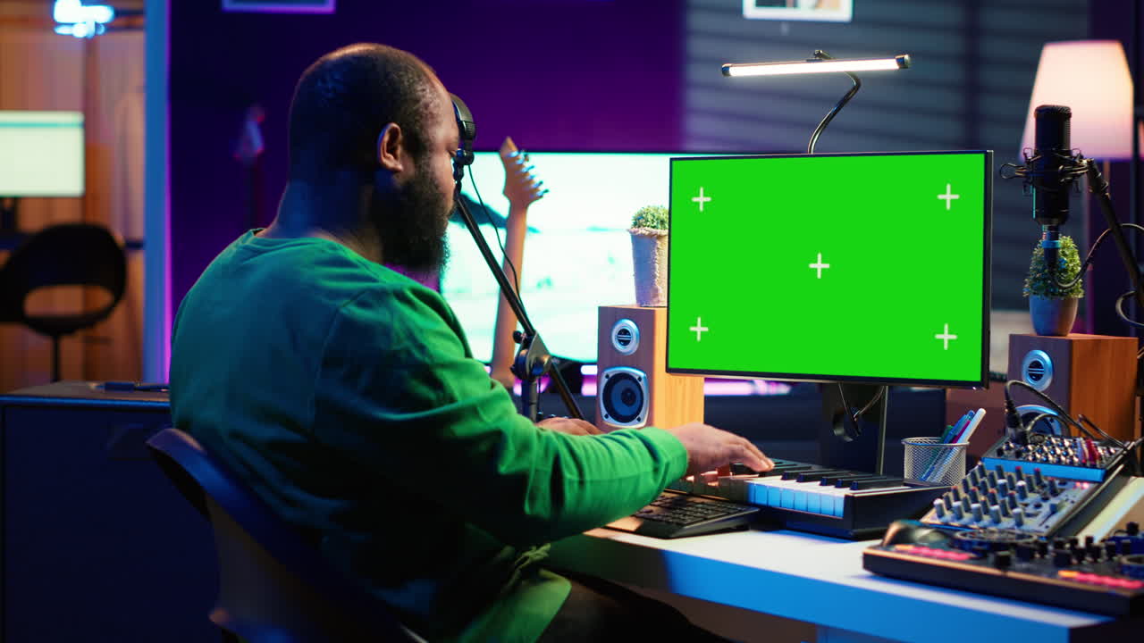 Artist plays midi controller synthesizer next to greenscreen layout