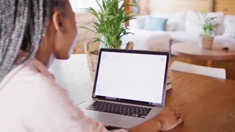 mujer afroamericana sentada a la mesa y usando una computadora portátil con espacio de copia para videollamada, cámara lenta