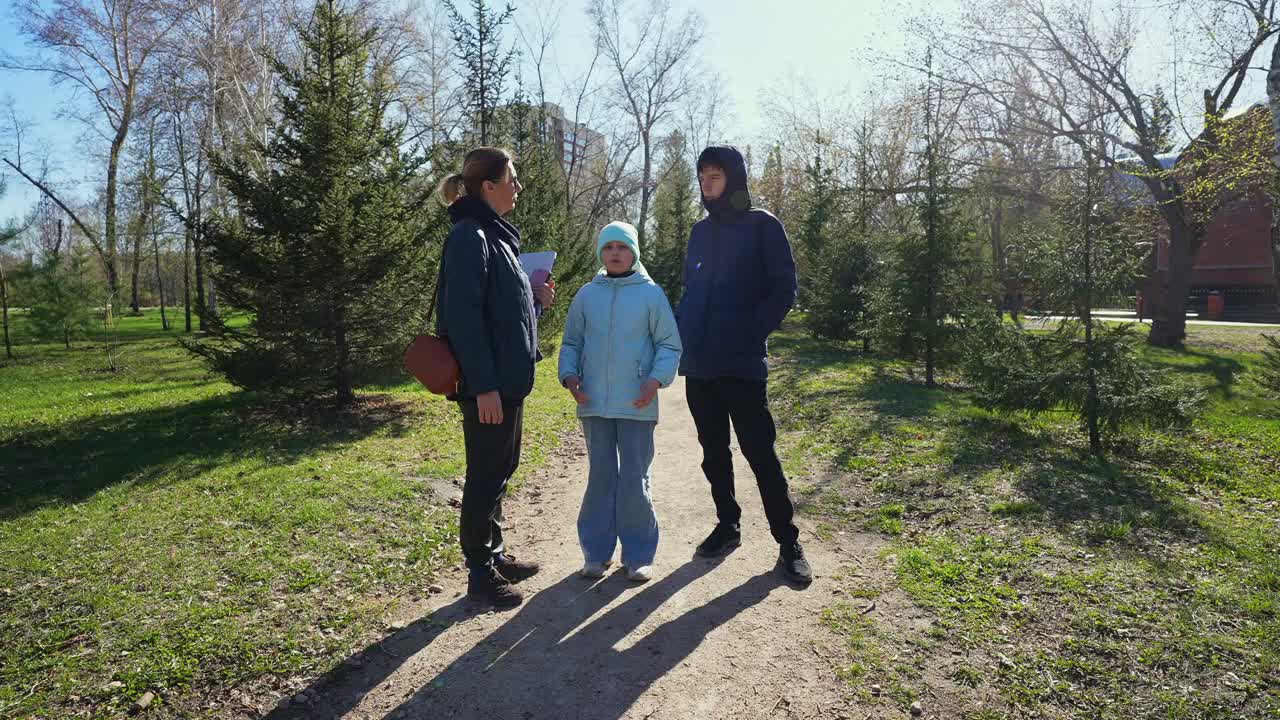 Donna, bambino e bambina che parlano in un parco soleggiato