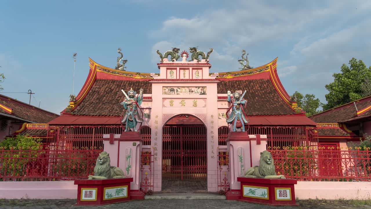 A vibrant pink and red traditional Chinese temple with ornate statues and a grand entrance gate