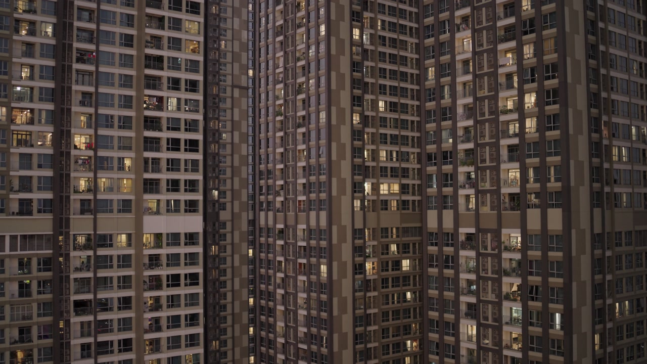 Dense urban residential towers in Ho Chi Minh City showcase illuminated windows at dusk. Modern high-rise apartment complexes reveal city life in Vietnam's largest metropolis.