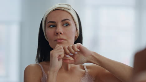 hermosa dama tocando la piel mirando el espejo en el interior de primer plano. cuidado de la belleza en casa