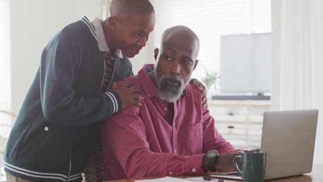 video of happy african american father and son using laptop