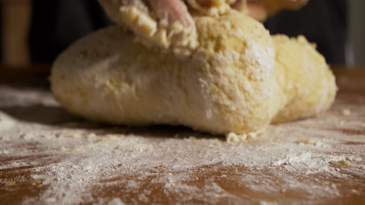 Ripresa 4K ravvicinata al rallentatore di impasto crudo per gnocchi impastato a mano su un tavolo di legno.