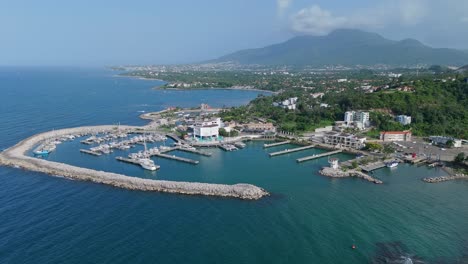 Aerial-circling-view-of-Marina-Ocean-World-harbour-with-breakwater-and-boats,-Puerto-Plata-Dominican-Republic