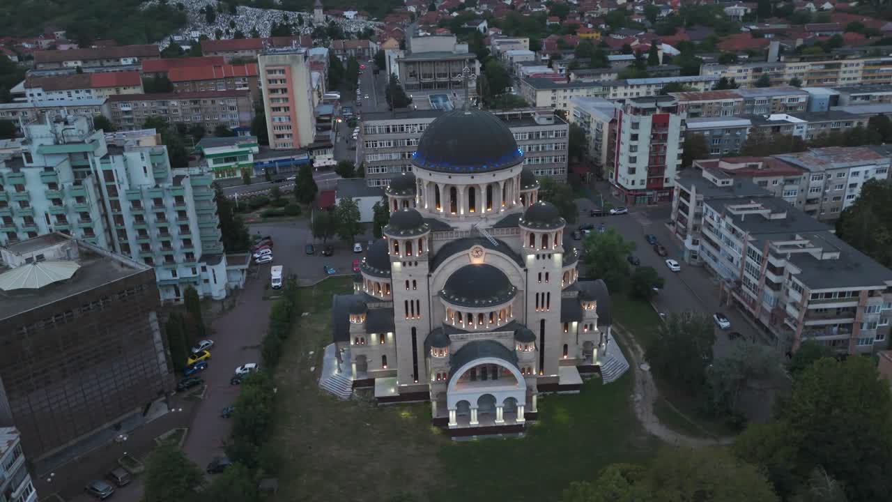 A smooth orbital drone shot capturing the cathedral at night, showcasing its warm lighting, ornate architecture, and surrounding quiet cityscape