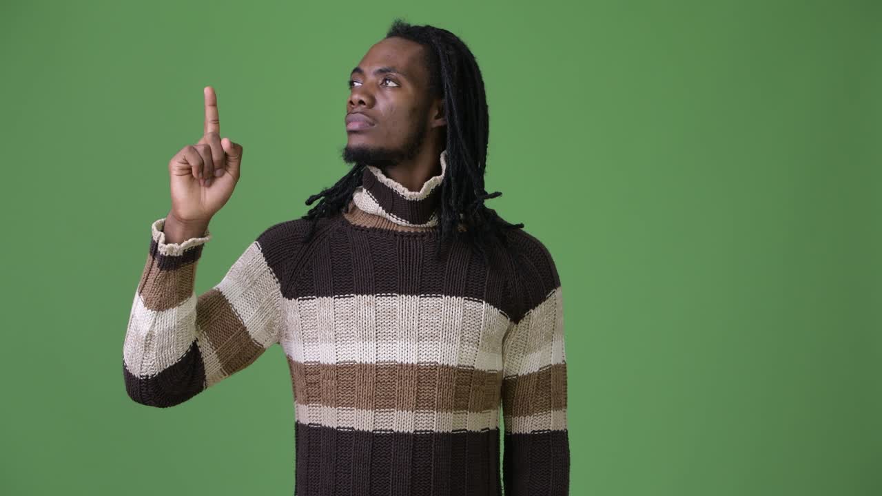 Young handsome African man with dreadlocks against green background