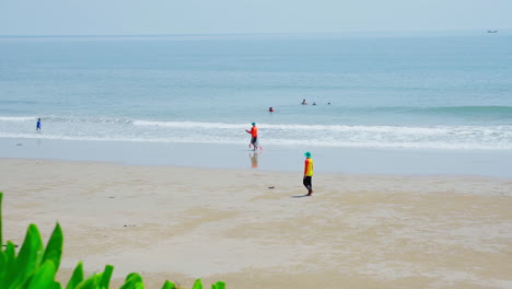 Aerial-view-of-two-lifeguard-man-and-woman-carrying-a-fish-net-walking-to-the-tropical-beach-sunny-with-bright-blue-sky