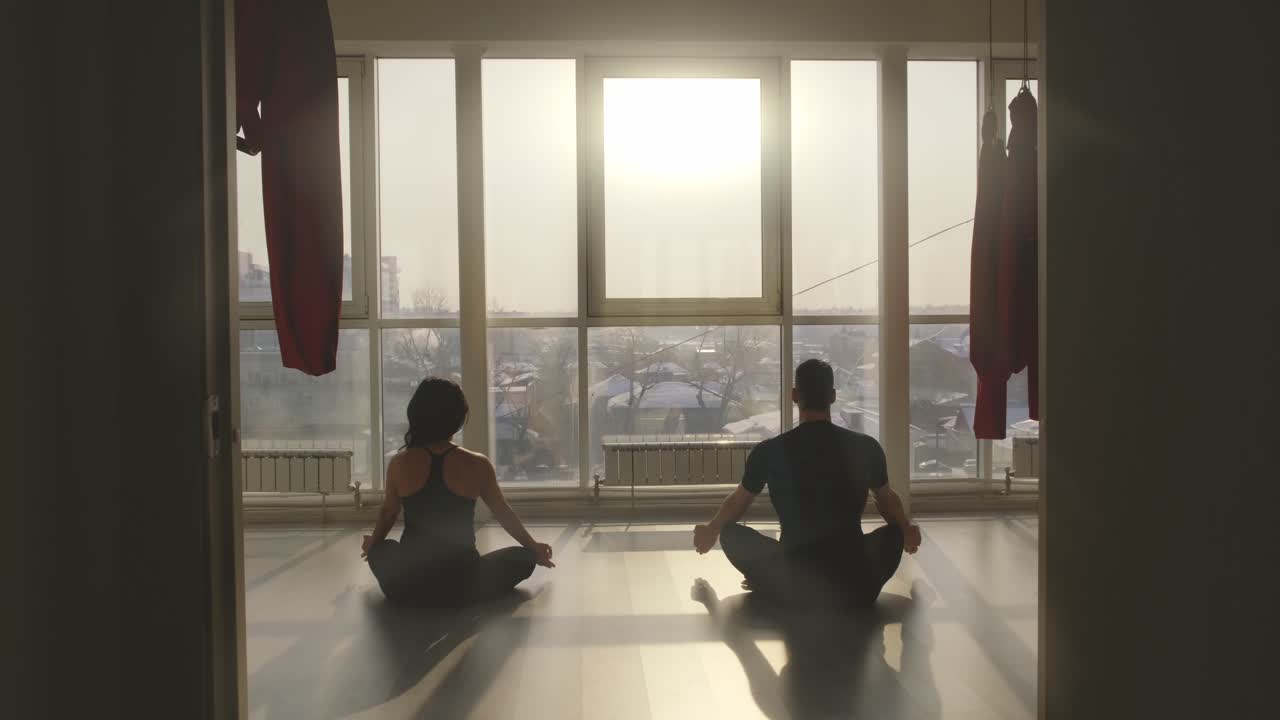 Couple Meditating by a Large Window