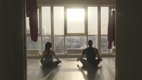 couple meditating by a large window