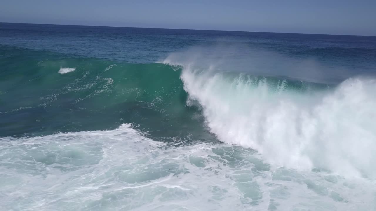 olas que se rompen sobre arrecifes poco profundos disparadas desde el frente con un dron