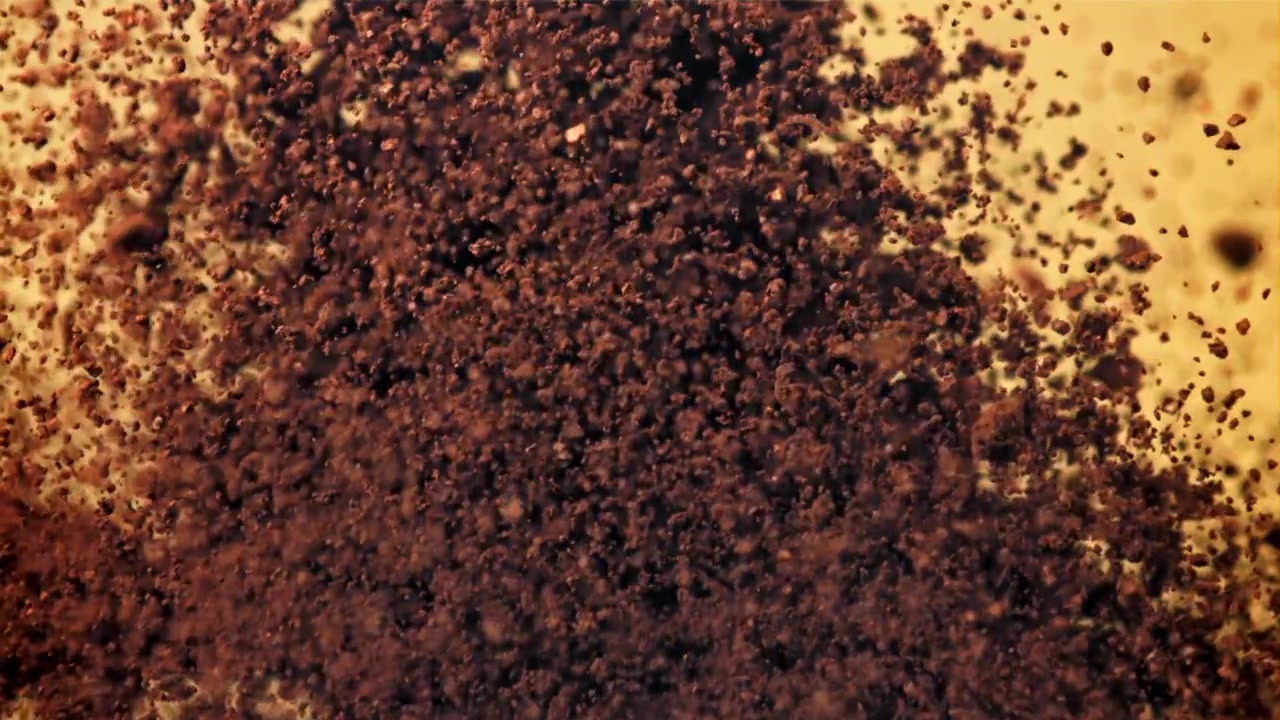 Dark Coffee Grounds Bursting and Scattering on Yellow Background