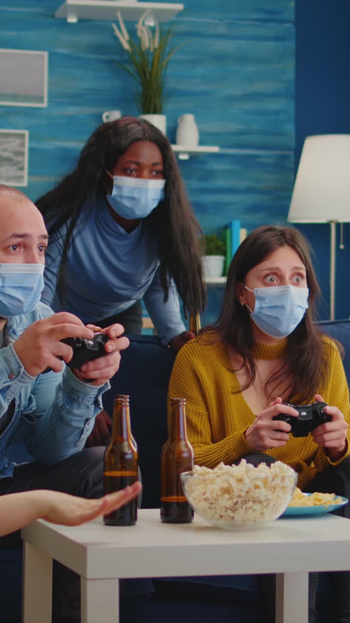 Vertical video: Concentrated multiracial friends playing video games with joystick