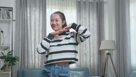 asian woman dancing while shooting video content for social networks at home