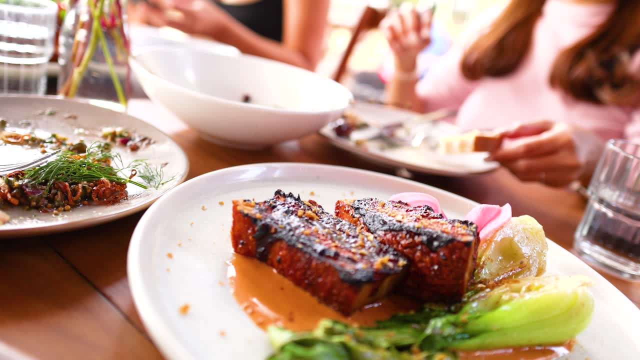 Crispy pork belly served in a vibrant restaurant setting, capturing a lively dining atmosphere with friends