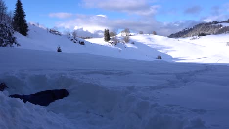 Persona-Cavando-Un-Montón-De-Nieve-Desde-Adentro-Y-Tirando-Nieve-Afuera-En-Un-Día-Claro-En-Los-Alpes