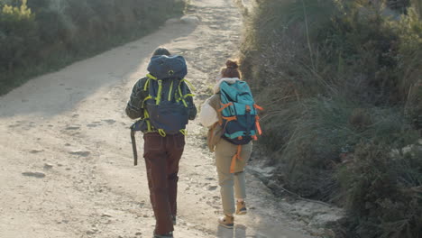 Toma-En-ángulo-Alto-De-Dos-Mujeres-Turistas-Caminando-Por-Un-Camino-De-Tierra-En-Un-Parque-Natural