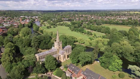 Holy-Trinity-historical-English-church-town-beside-river-Avon-weir,-Stratford-Upon-Avon-countryside-aerial-view