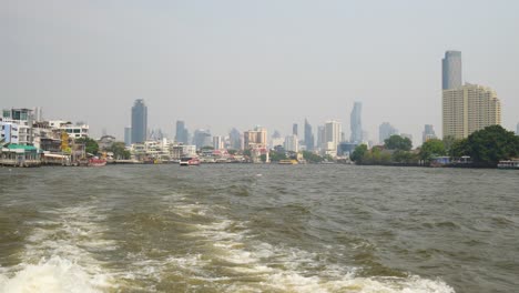 chao phraya river bustling with activity, city skyline in the background in bangkok, thailand