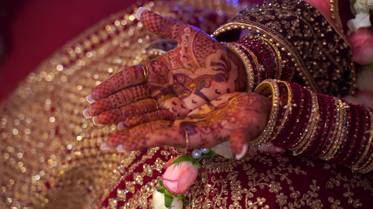Beautiful Indian bride in wedding dress showing henna tattoo art made on her hands. Wearing extravagant make up and jewellery during hindu themed religious ceremony