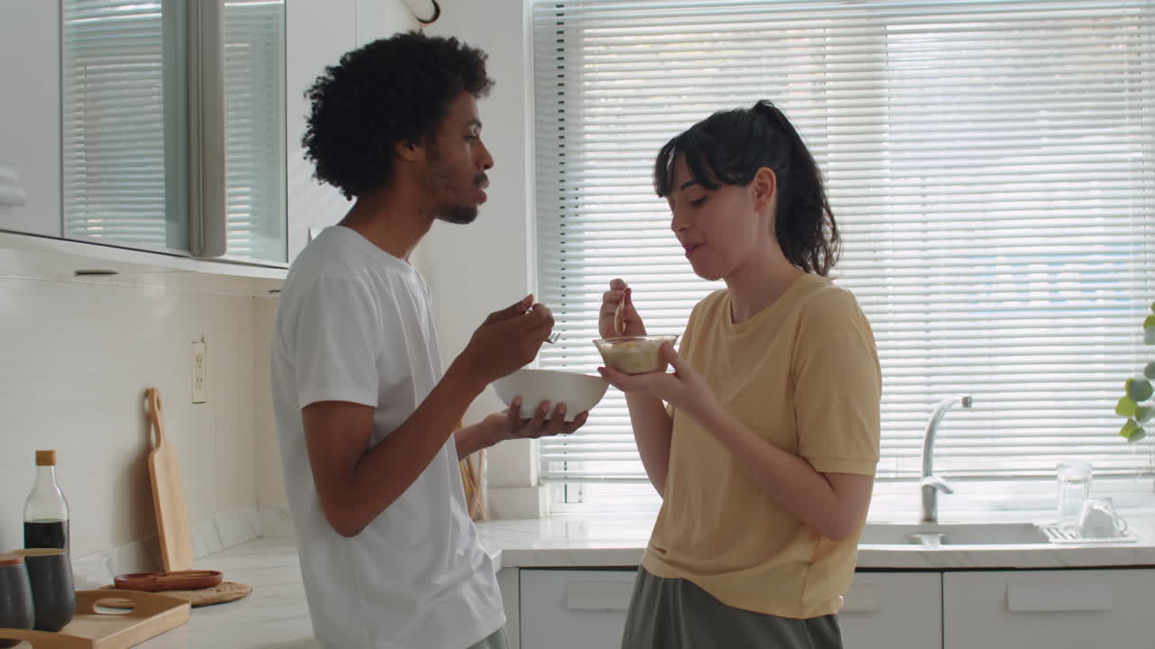 Casal intercultural tomando café da manhã e conversando em casa