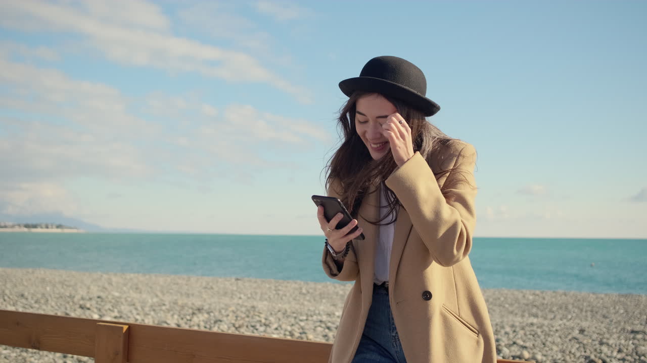 해변에서 전화를 사용하는 여자