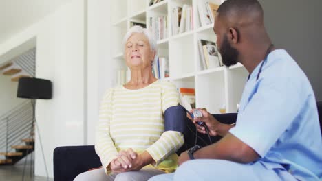 Vídeo-De-Un-Feliz-Médico-Afroamericano-Comprobando-La-Presión-A-Una-Mujer-Mayor-Caucásica