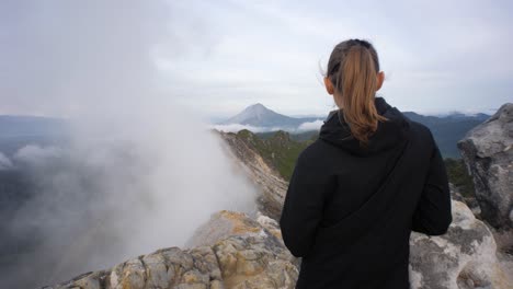 slow motion shot of young female hiker enjoying the view from mount sibayak volcano in north sumatra, indonesia