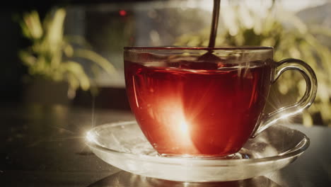 agita el azúcar en una taza de té con una cucharadita. buen día, la luz de la ventana ilumina la taza.