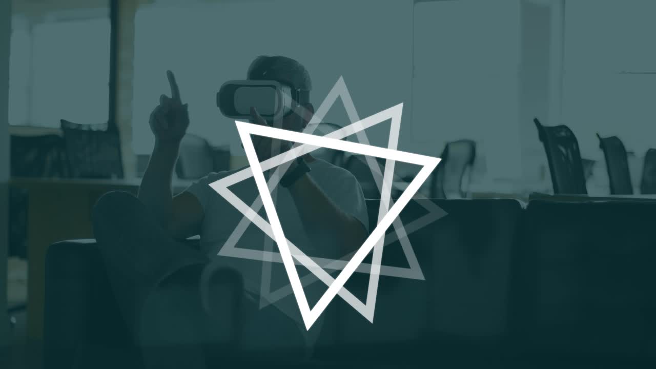 Animación de triángulos girando sobre un hombre caucásico usando un casco de realidad virtual en una oficina.