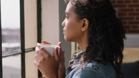 happy-young-woman-drinking-coffee-at-home-enjoying-relaxed-morning-looking-out-window-thinking-planning-ahead-in-cozy-apartment-loft