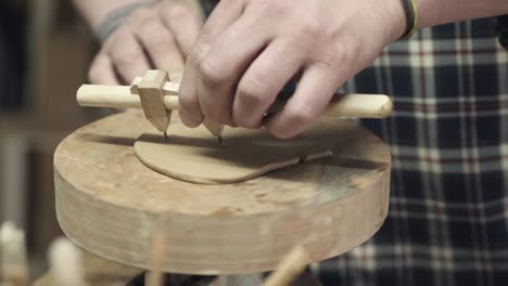 a potter cuts a circle of clay with a compass